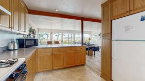 A kitchen with wooden cabinets, a stove, a microwave, and a refrigerator. - Waterfront house with bay and ocean views large deck and quiet location (Lincoln City)