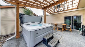 Een hottub onder een houten pergola, met een tafel en stoelen in de buurt.