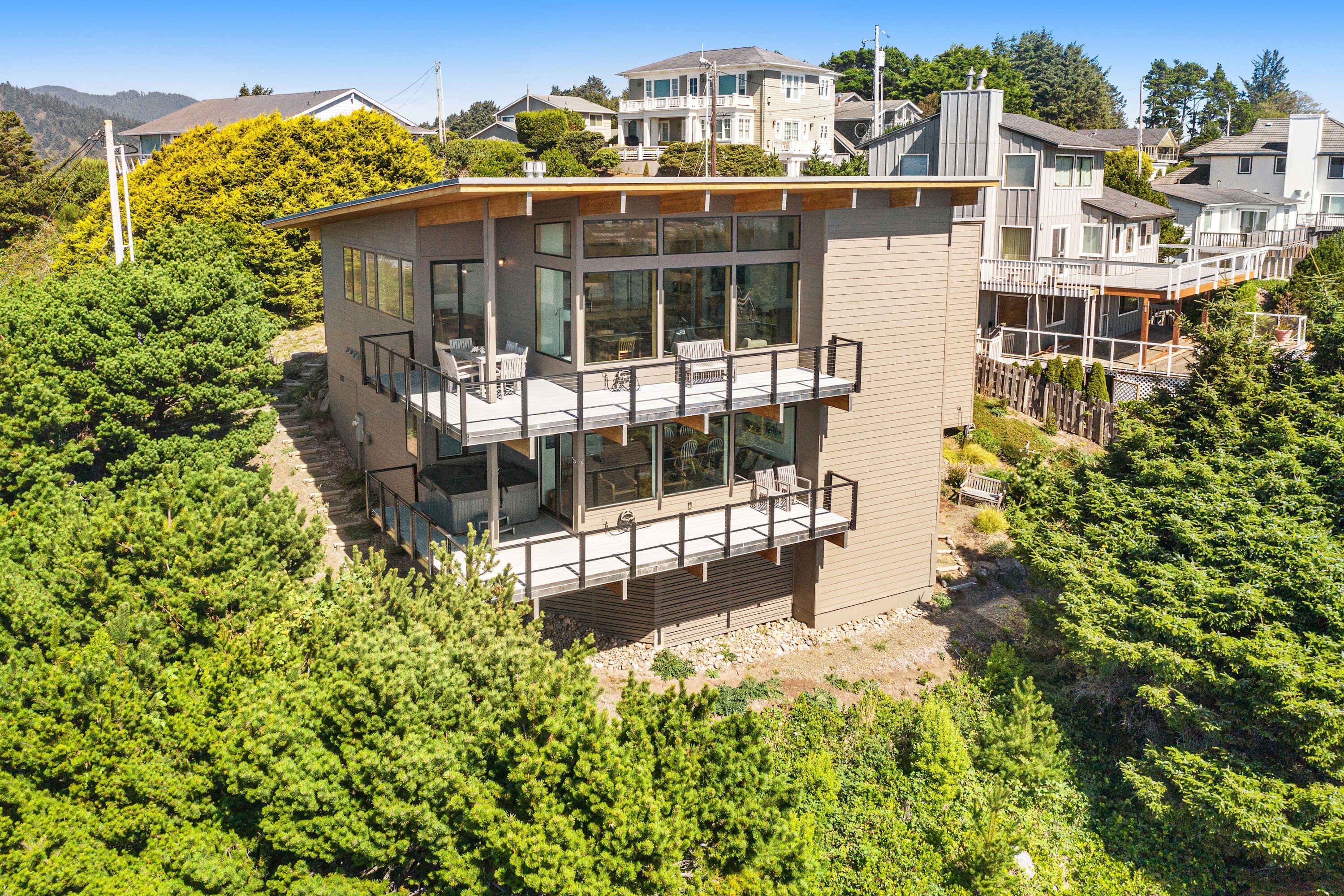 Ein modernes, zweistöckiges Haus mit Balkon, umgeben von üppigem Grün.