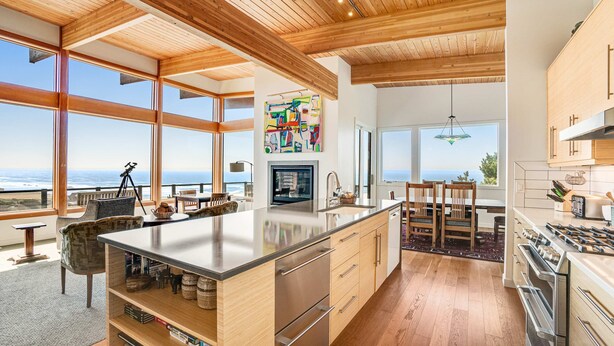 A modern kitchen with large windows, a central island, and a view of the ocean. - New home with unparalleled ocean views and private hot tub dogs welcome (Lincoln City)