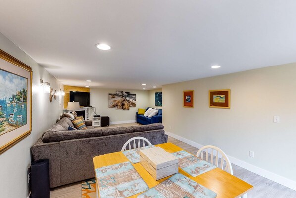 A dining area with a wooden table and chairs, a sofa, and artwork on the walls. - Charming three story getaway with two cozy living areas walk to the beach (Lincoln City)