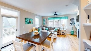 A spacious living area with a wooden dining table, white chairs, a grey sofa, and a teal accent wall. - Charming three story getaway with two cozy living areas walk to the beach (Lincoln City)