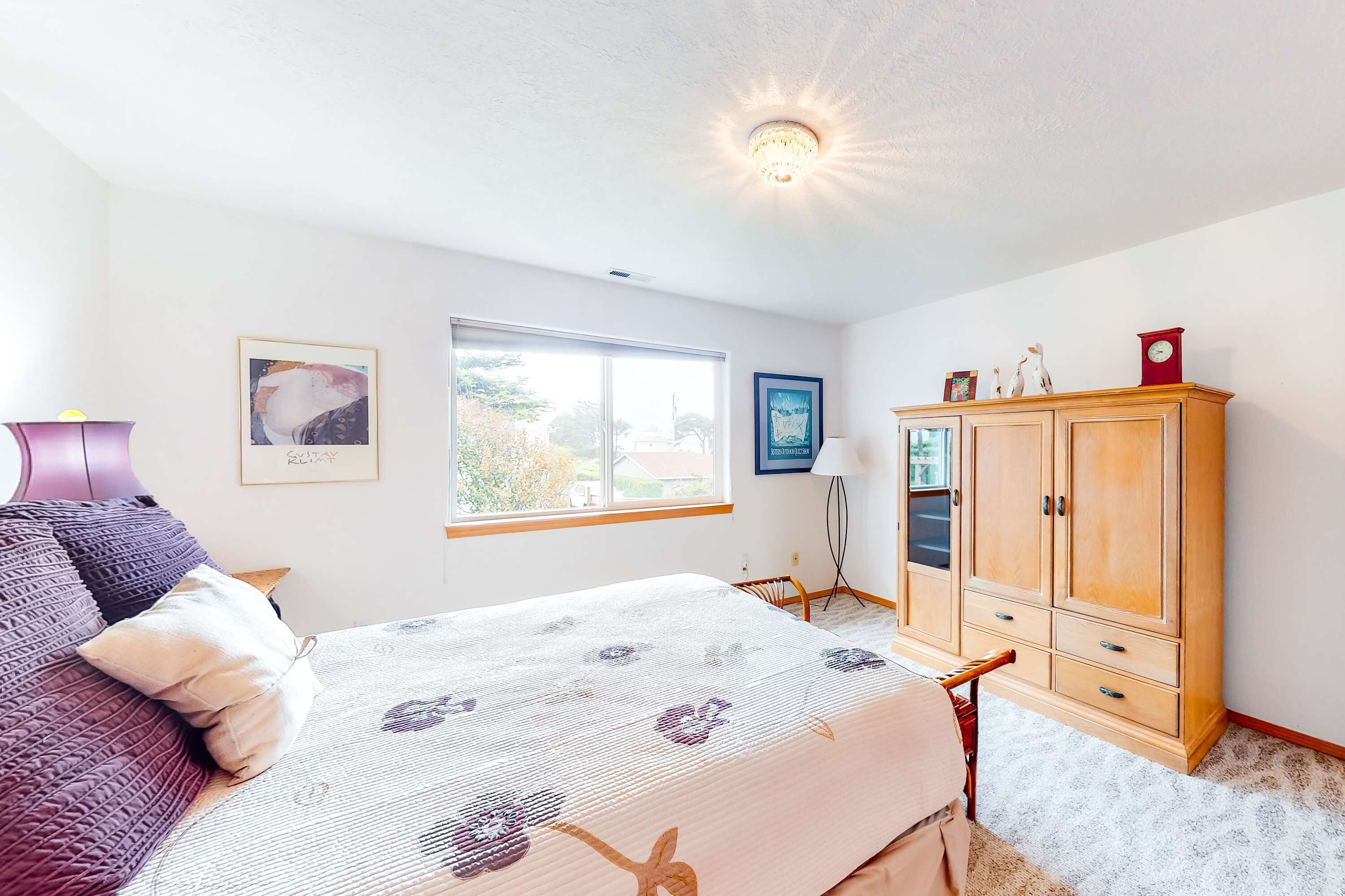 A bedroom with a bed, a wardrobe, a window, and a ceiling light.