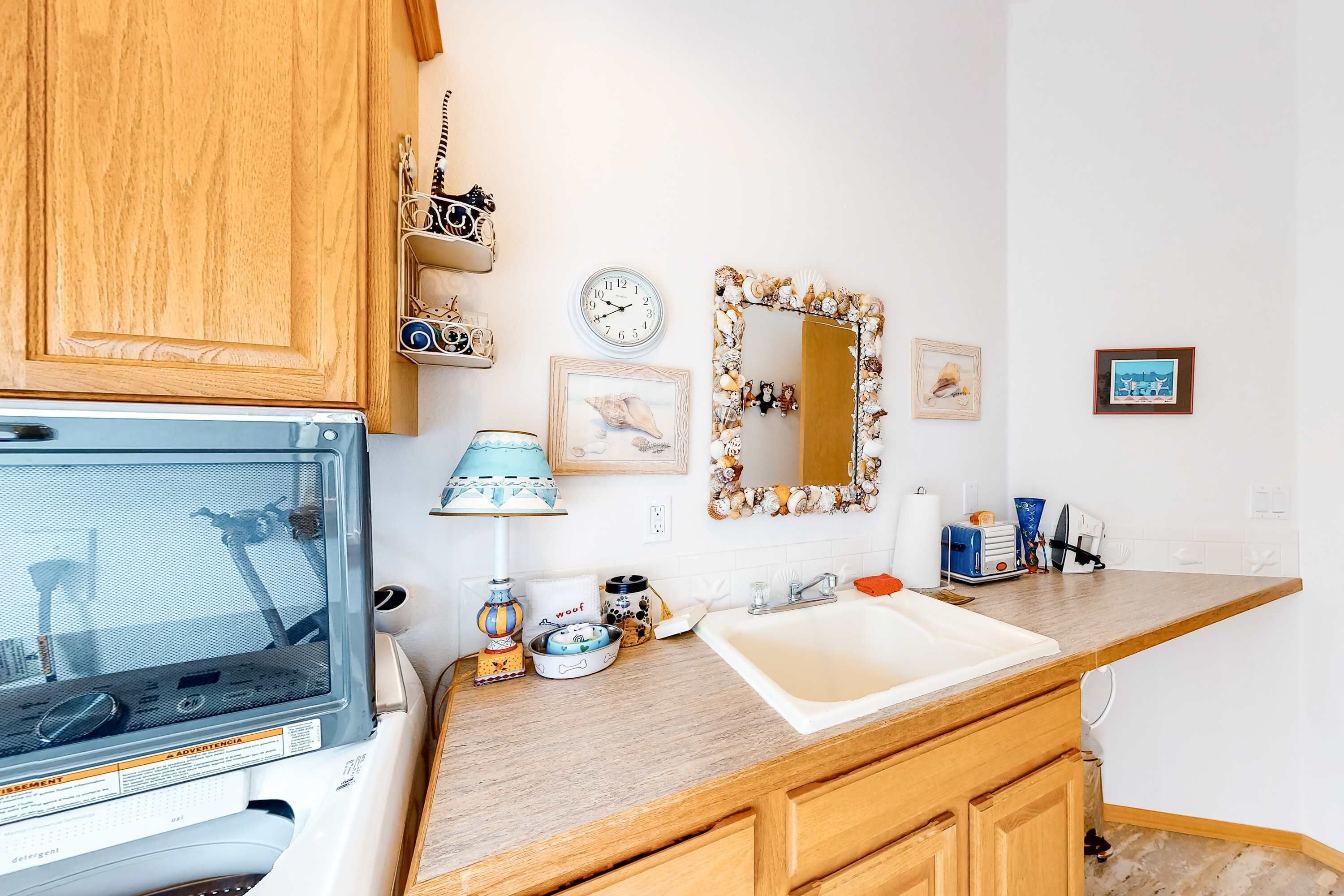 Una cocina con armarios de madera, microondas, pileta y diversos objetos decorativos sobre la encimera.