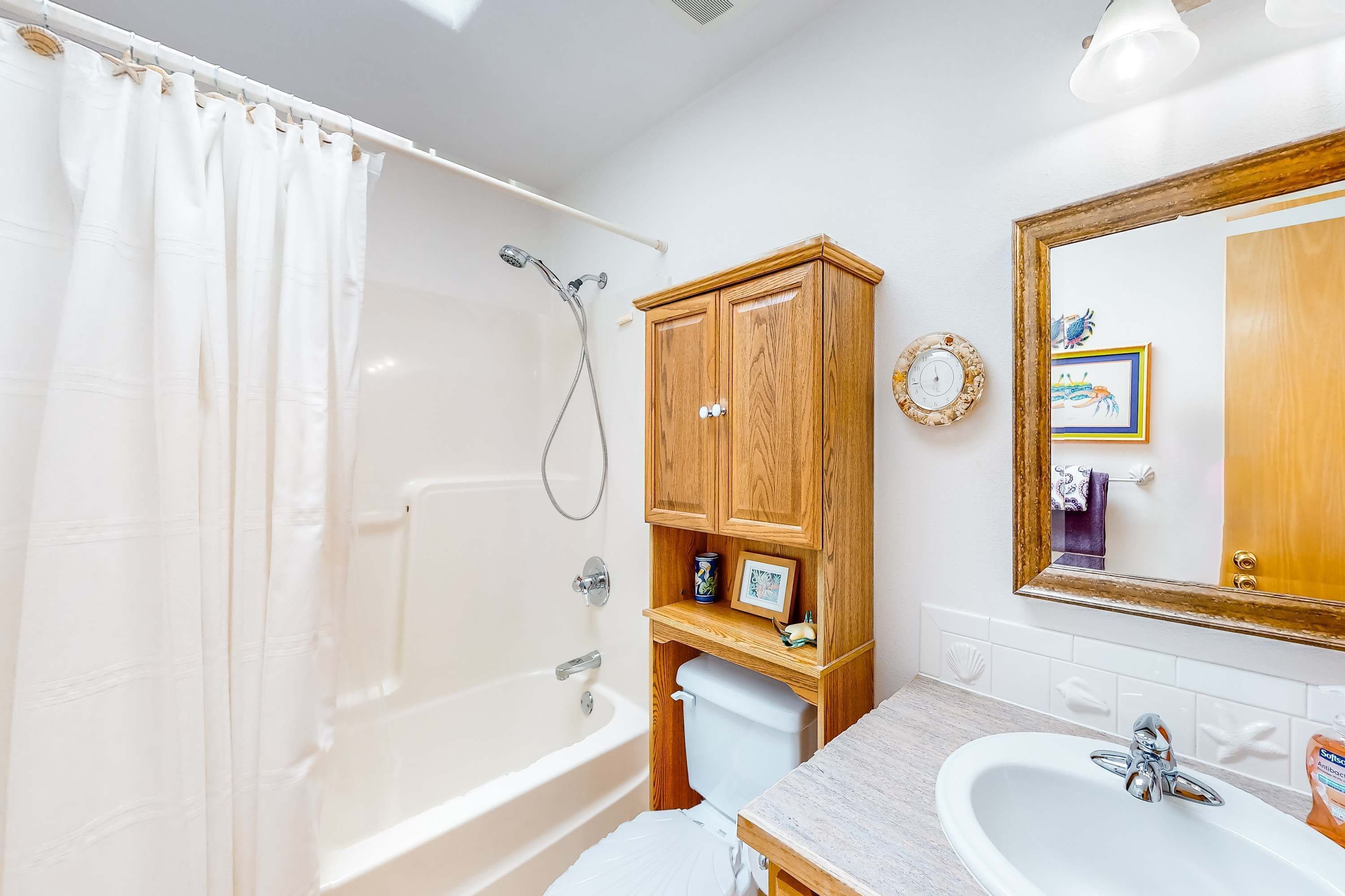 A bathroom with a bathtub, a toilet, a sink, and wooden cabinets.
