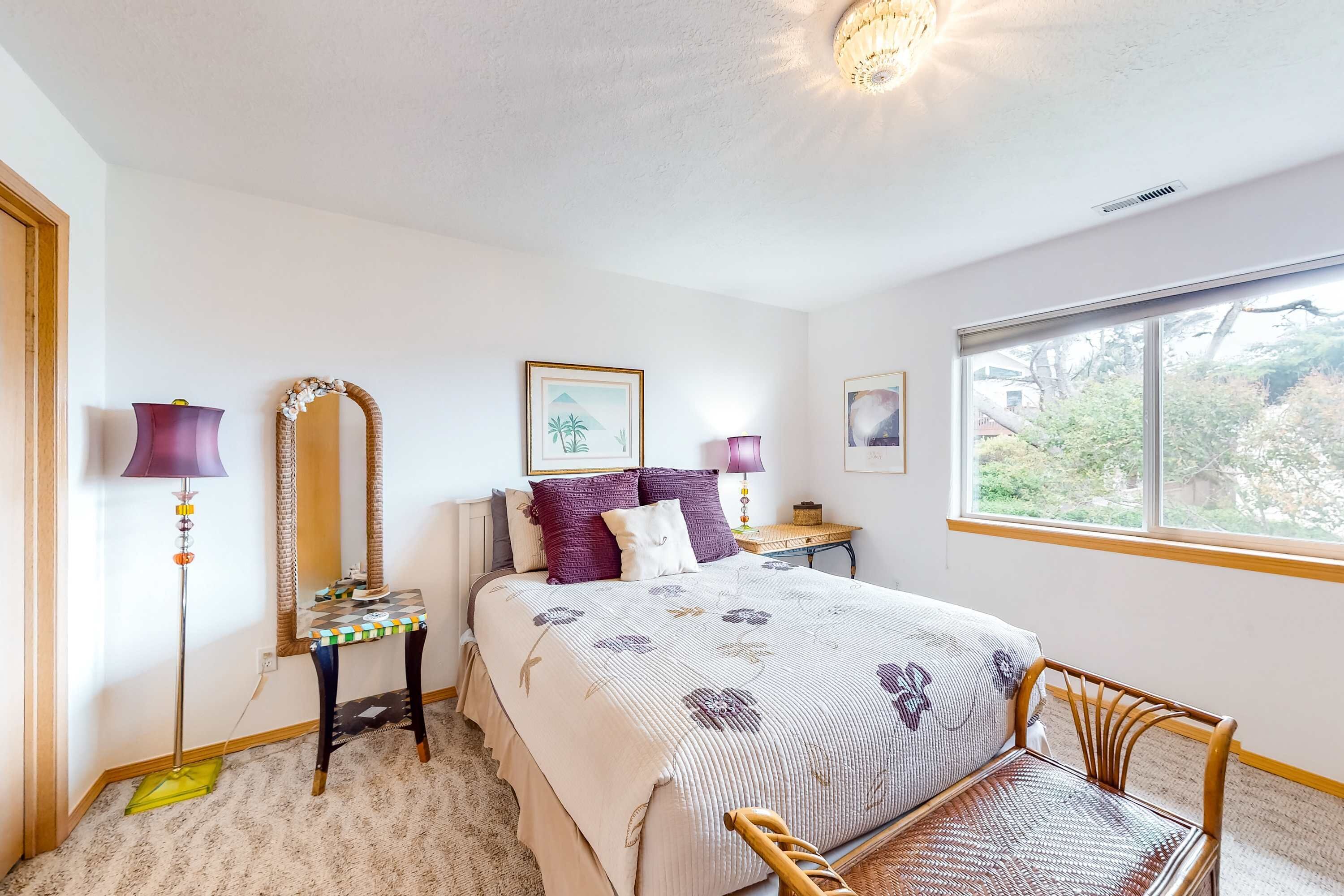 Une chambre à coucher avec un lit, des lampes de chevet, un miroir, une fenêtre et une chaise.