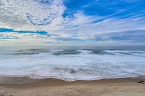Een strand met golven en een heldere lucht.