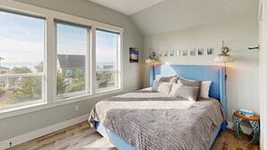 A bedroom with a large window, a bed with a blue headboard, and a small side table. - Wonderful coastal escape in the trees with private hot tub and fast WiFi dogs OK (Lincoln City)