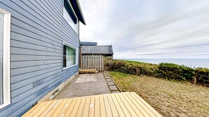 Una casa moderna con una terraza de madera, un pequeño porche y vista al mar.