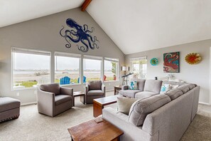 A spacious living room with a high ceiling, large windows, and a view of the cityscape. - Dog Friendly Bayfront Beauty with a Private Hot Tub Free WiFi and Washer Dryer (Lincoln City)