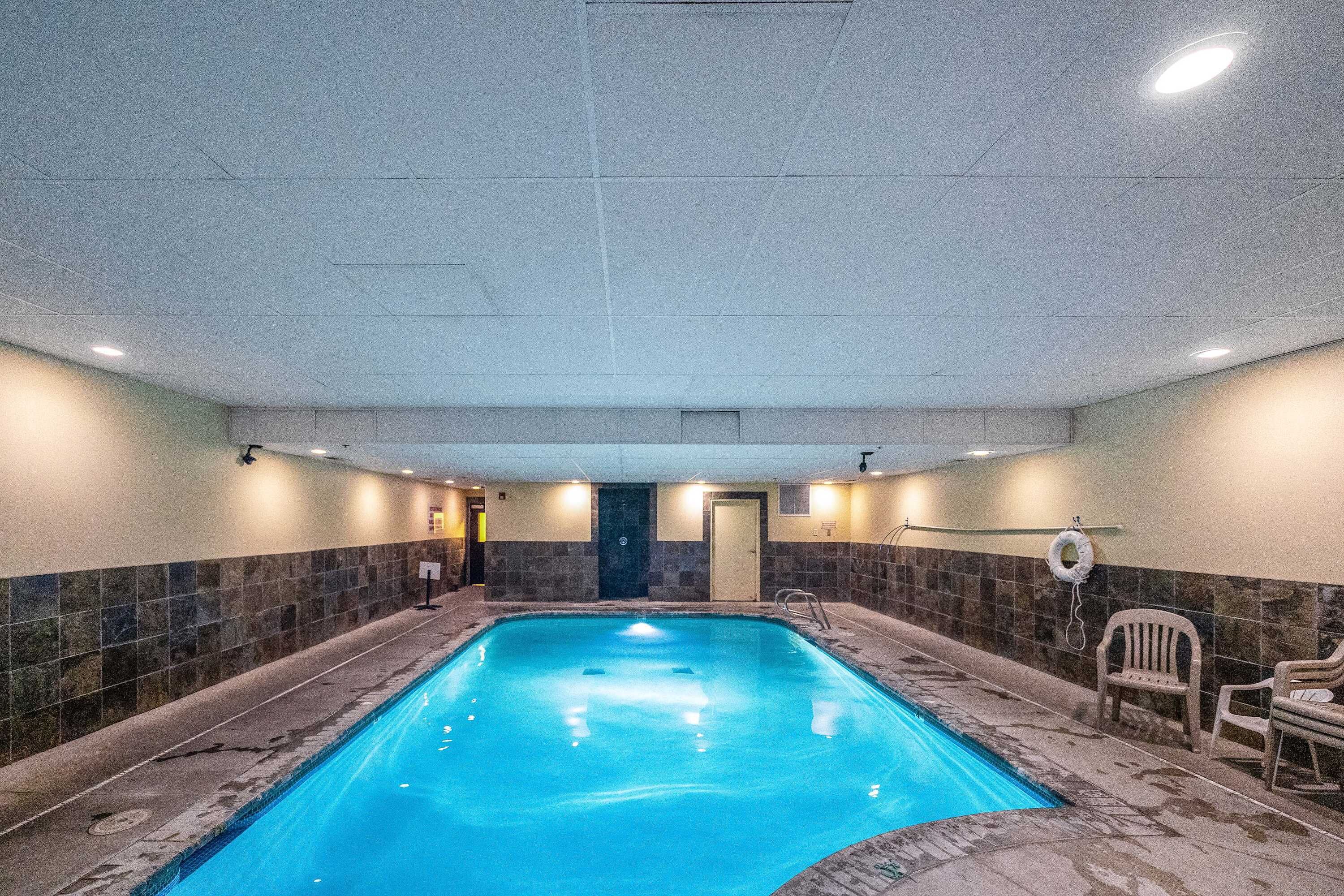 An indoor swimming pool with tiled walls and a door at the far end.