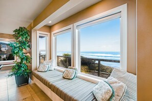 A cozy seating area with a view of the ocean, a potted plant, and a window with a view of the beach. - Stunning Oceanfront Retreat with Full Kitchen Private Hot Tub High Speed WiFi (Lincoln City)