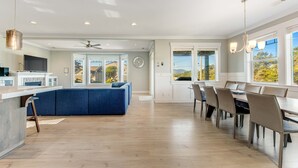 Een moderne keuken met een blauwe bank, een eethoek met stoelen en grote ramen.