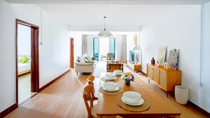Un vaste espace dédié à la salle à manger, avec une table en bois dressée pour quatre personnes, un canapé et un meuble contenant des objets décoratifs.