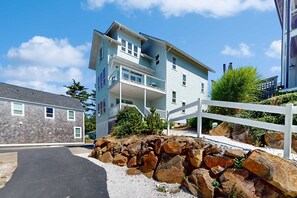 A multi-story residential building with a balcony, a driveway, and a white fence. - Ocean Views, Hot Tub & Coastal Comfort (Lincoln City)