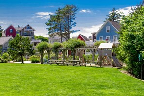 A playground with a wooden structure and slides, surrounded by a well-maintained lawn and houses in the background. - Ocean Views, Hot Tub & Coastal Comfort (Lincoln City)