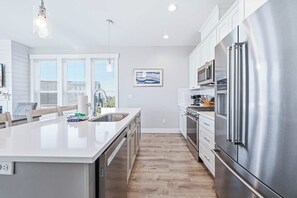 A modern kitchen with stainless steel appliances, a large island, and a view of the outdoors. - Ocean Views, Hot Tub & Coastal Comfort (Lincoln City)