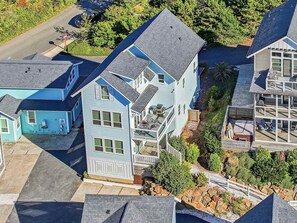 Un edificio residenziale a più piani con un balcone, una strada privata e una casa vicina.