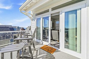 A balcony with outdoor seating and a doormat with a message. - Ocean Views, Hot Tub & Coastal Comfort (Lincoln City)