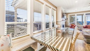 Un salon spacieux doté de grandes fenêtres, d’une table basse en verre et d’un coin salon confortable.