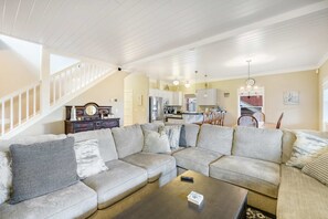 Ein geräumiges Wohnzimmer mit einer großen Eckcouch, einem dunklen Couchtisch und einer Treppe, die zu einer oberen Ebene führt.