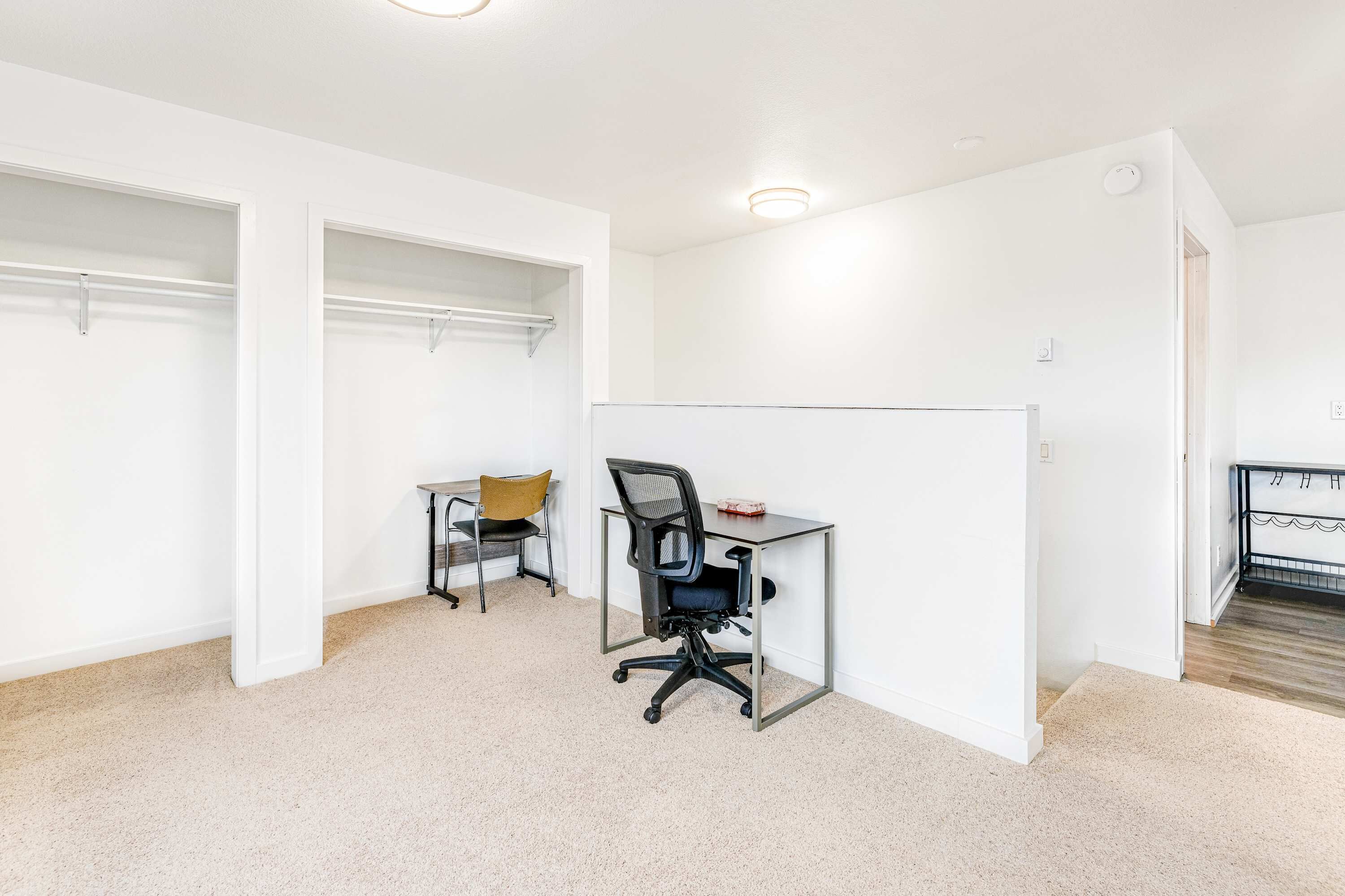 A room with a desk, office chair, and shelving unit.
