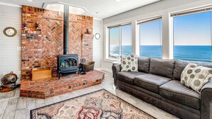 Un salon chaleureux avec une cheminée en briques, un canapé en cuir et de grandes fenêtres donnant sur la mer.