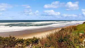 Eine Küstenlandschaft mit Strand, Wellen und blauem Himmel.