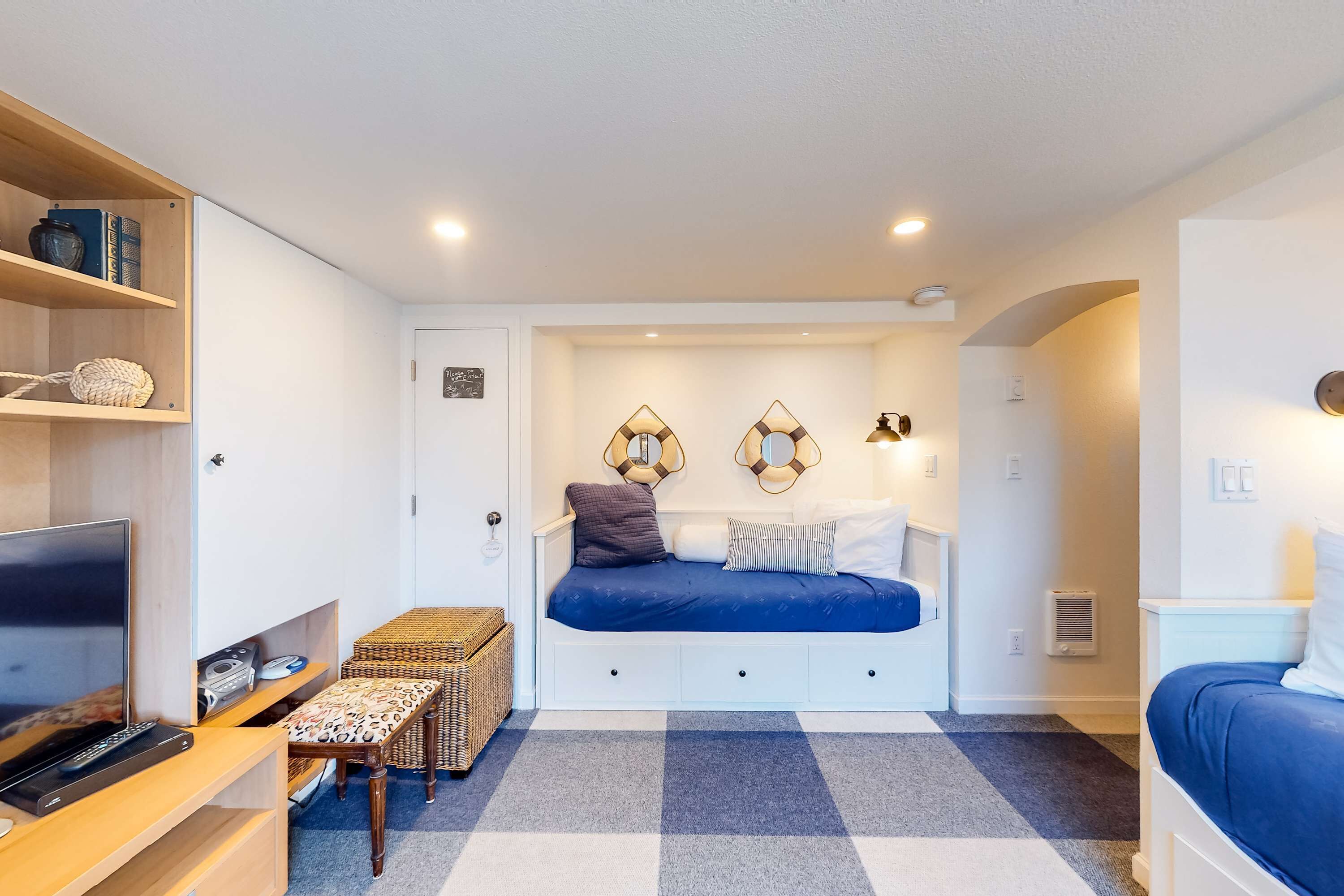 A compact bedroom with a bed, a TV, a small table, and a bookshelf.
