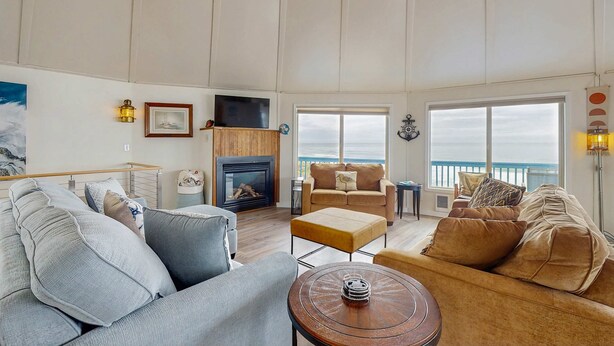 Uma sala de estar espaçosa com lareira, uma janela ampla com vista para o mar e uma varanda.
