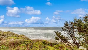 Paisagem costeira com praia, oceano e vegetação.
