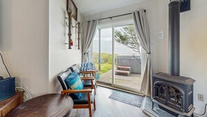 Um quarto acolhedor com uma mesa de madeira, cadeiras, um sofá e uma lareira a lenha preta.