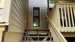 Eine Holztreppe mit Handlauf führt zu einer Tür mit einem Fenster.
