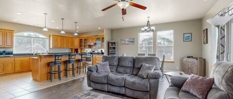 A spacious living room with a grey sofa, a coffee table, and a ceiling fan.