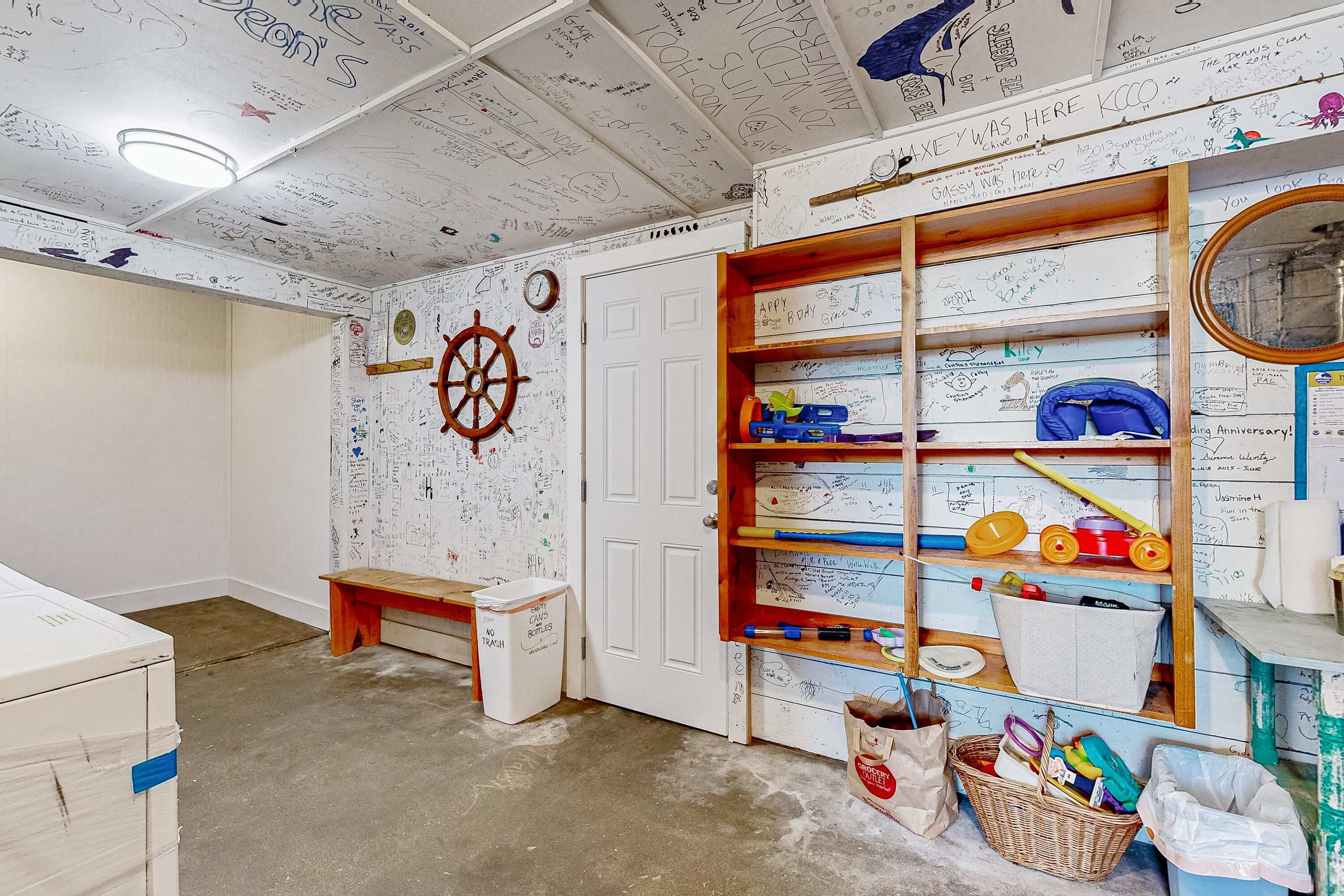 Een kamer met een witte deur, een houten plank met diverse spullen, een wandklok en een decoratie van een scheepsschroef.