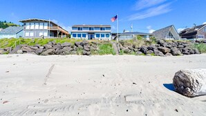 Een strandhuis met een groot gebouw, een vlag en een rotsachtige kustlijn.