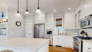 Una cocina moderna con armarios blancos, electrodomésticos de acero inoxidable y encimera de granito.