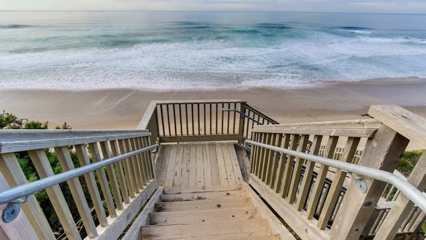 Una escalera de madera que conduce a una playa con vista al océano.