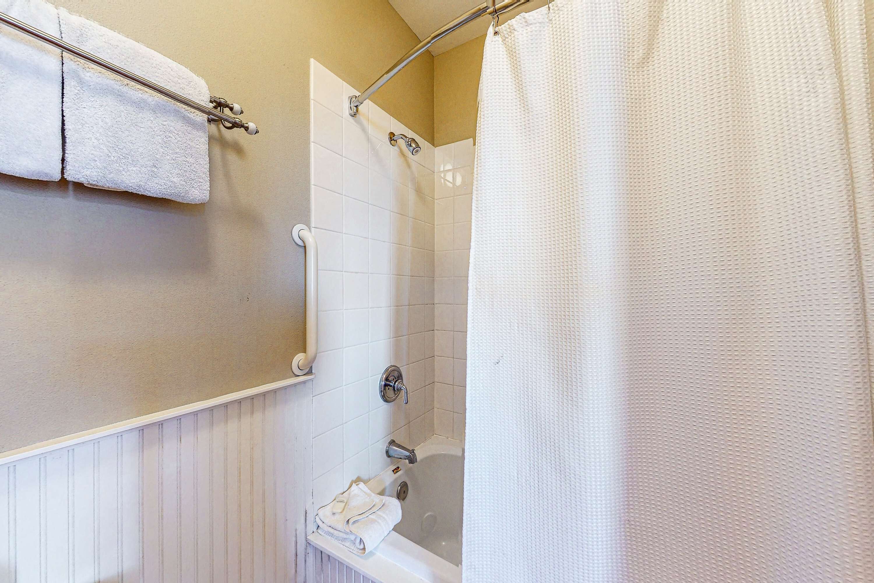 A bathroom with a bathtub, a shower, and a towel rack with towels.