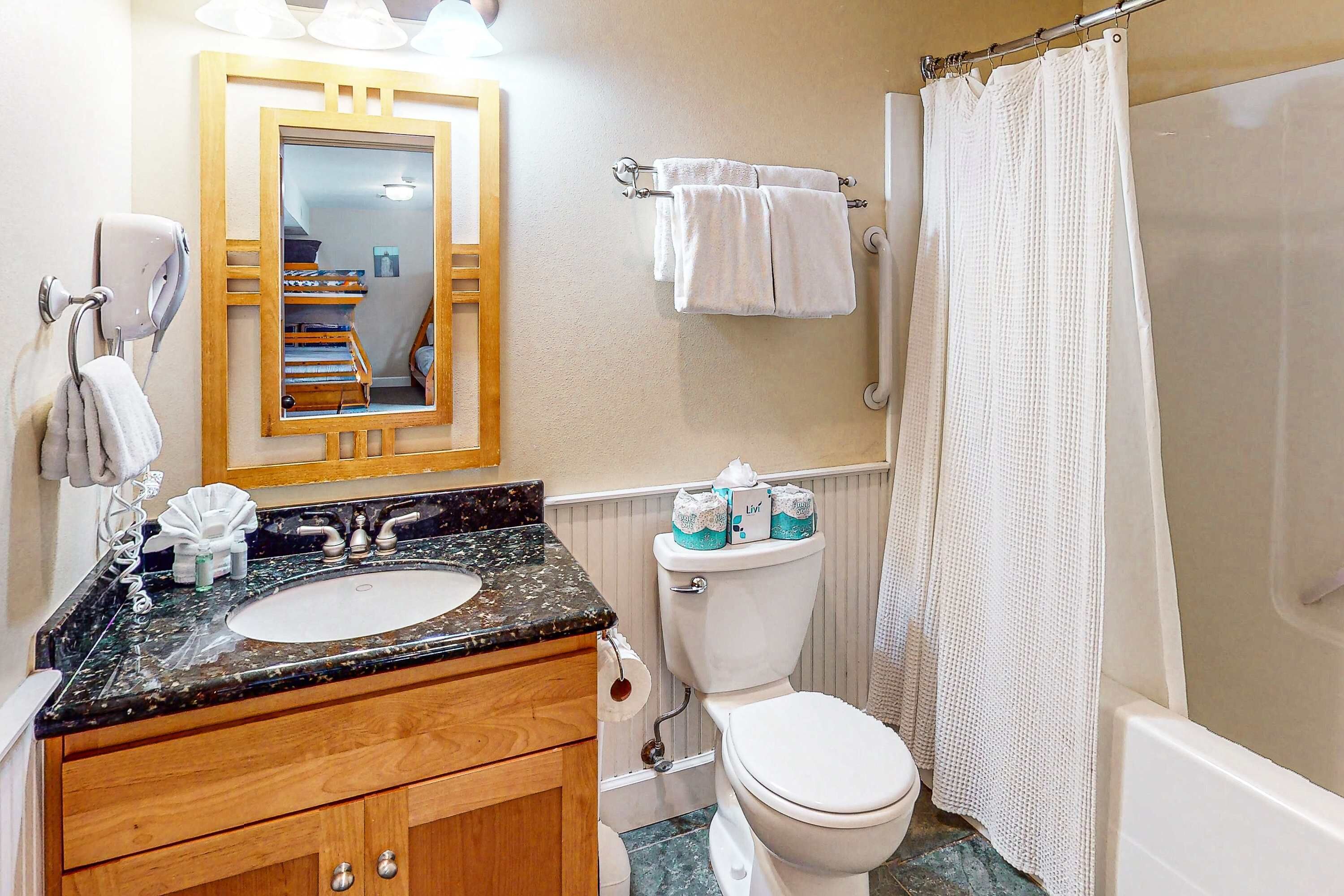 Un baño con lavabo, espejo, inodoro y cortina de ducha.