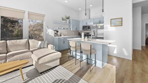 Een moderne keuken met een centraal eiland, barstoelen en een zithoek met een bank en salontafel.