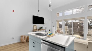 Een moderne keuken met een groot eiland, een inbouwvaatwasser en een flatscreen televisie aan de muur.