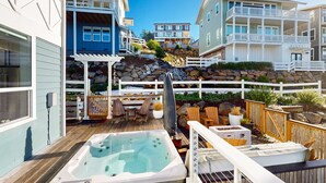 Ein Wohngebiet mit einer Holzterrasse, einem Whirlpool, Gartenmöbeln und einer Steinmauer.