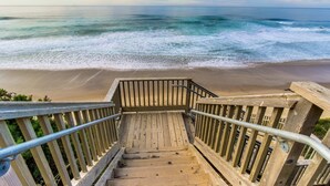 Eine Holztreppe führt zu einem Strand mit Blick auf das Meer.