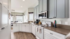 Una cocina moderna con armarios blancos, una estufa de acero inoxidable y un microondas.