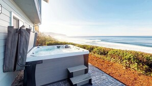 Un jacuzzi con escalones que llevan a un patio con vistas al océano.