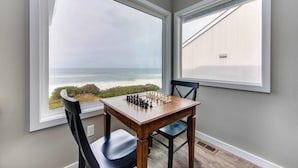 Un tablero de ajedrez sobre una mesa junto a una ventana con vistas al océano.