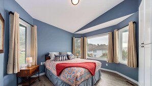 Un dormitorio con una cama grande, una mesita de noche y una ventana con cortinas.