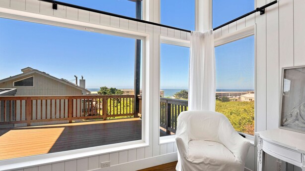 A balcony with a wooden deck, white walls, and a white chair. - Spacious home with ocean view enclosed yard fireplace hut tub washer and dryer (Lincoln City)