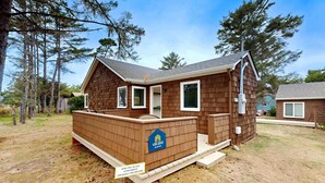 A small, single-story wooden cabin with a front porch and a mailbox.